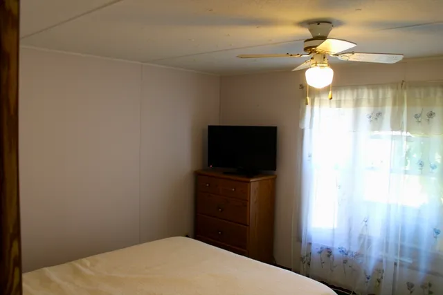 a bedroom with a bed and a flat tv screen on dresser