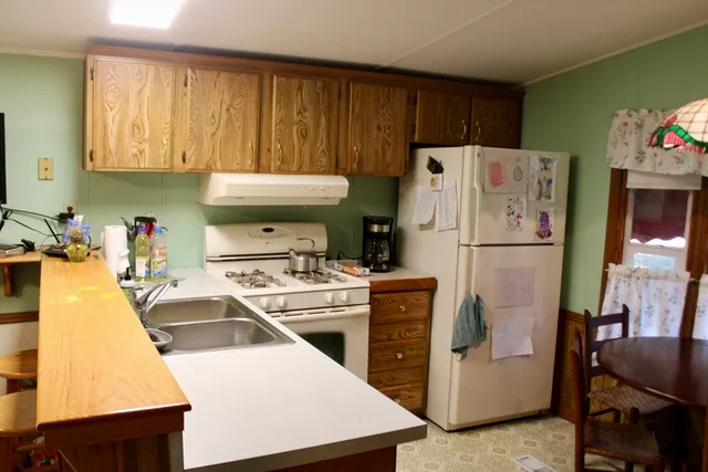 a kitchen with a refrigerator a stove a sink and wooden floor