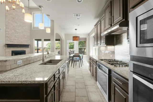 a kitchen with stainless steel appliances granite countertop a stove a sink and a microwave