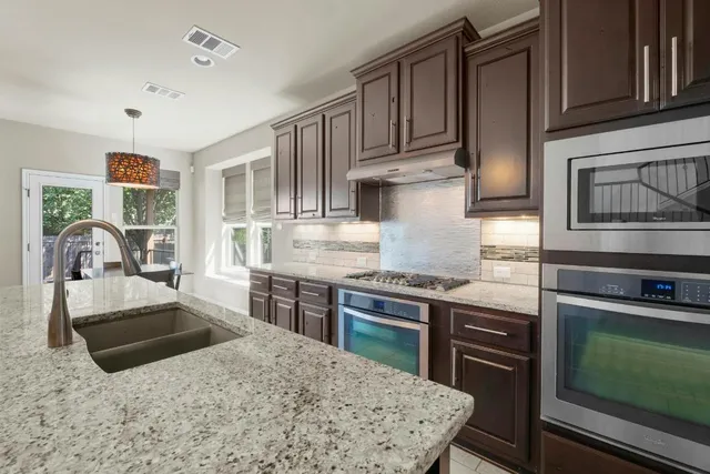 a kitchen with stainless steel appliances granite countertop a stove top oven a sink and dishwasher