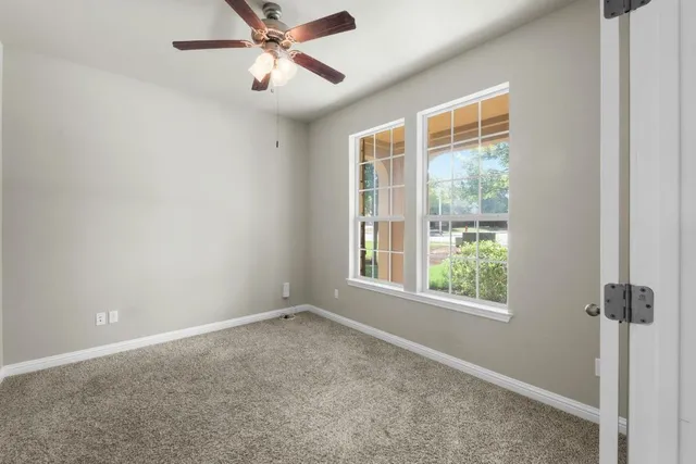an empty room with a window and a fan