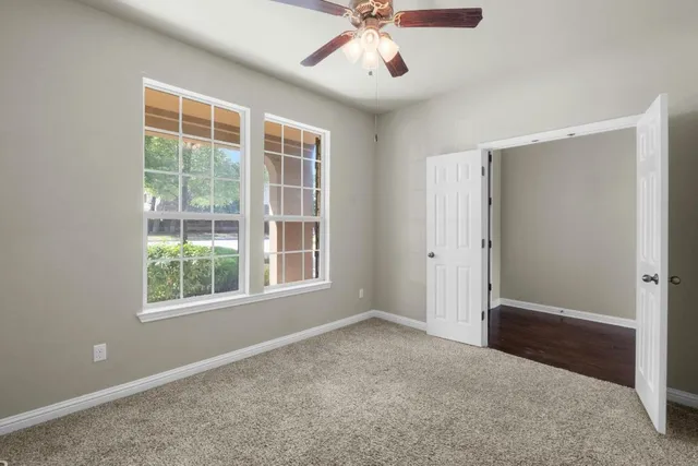 an empty room with a window and a ceiling fan