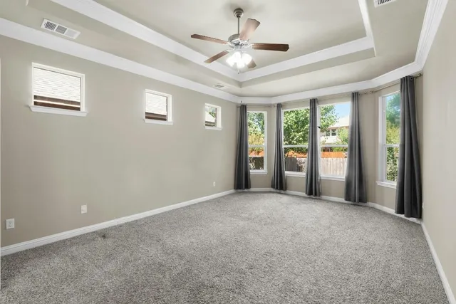 an empty room with windows and ceiling fan