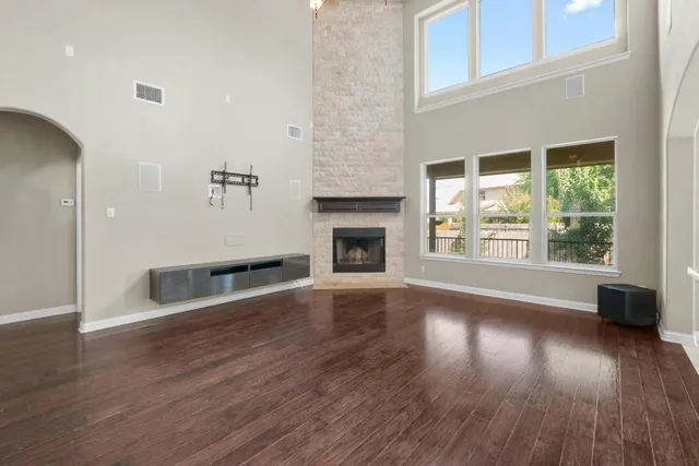 an empty room with wooden floor fireplace and windows