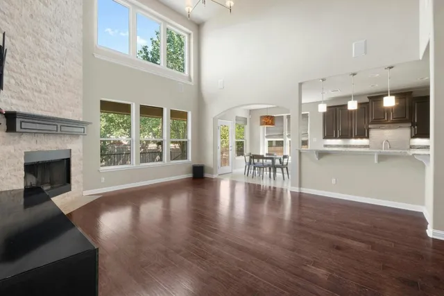 a view of an empty room with wooden floor and a fireplace