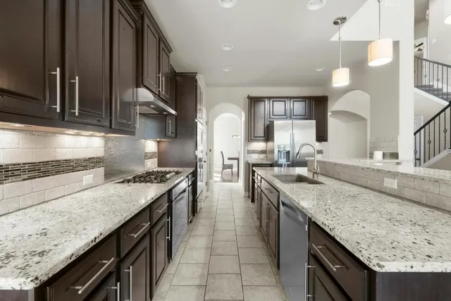 a kitchen with stainless steel appliances granite countertop a sink counter space a stove and a wooden cabinets