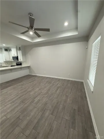 an empty room with wooden floor fan and windows