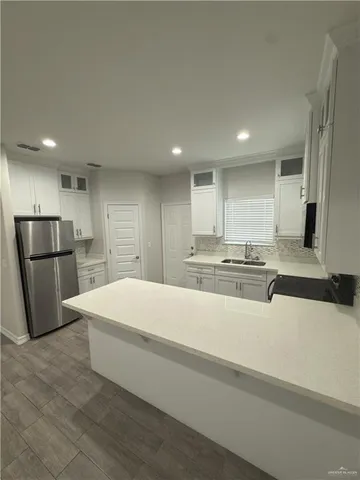 a large white kitchen with wooden floors and stainless steel appliances
