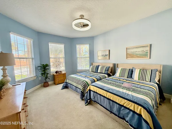 a spacious bedroom with two beds and potted plant
