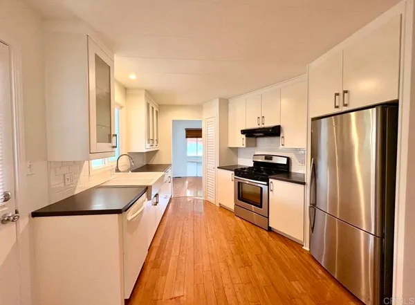 a kitchen with granite countertop stainless steel appliances a refrigerator a sink and a stove