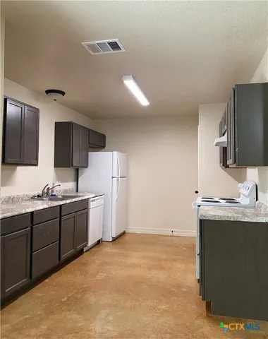 a kitchen with granite countertop a sink stove and refrigerator