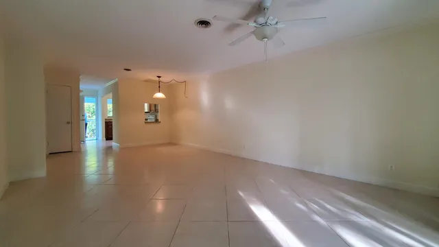 an empty room with chandelier fan and windows