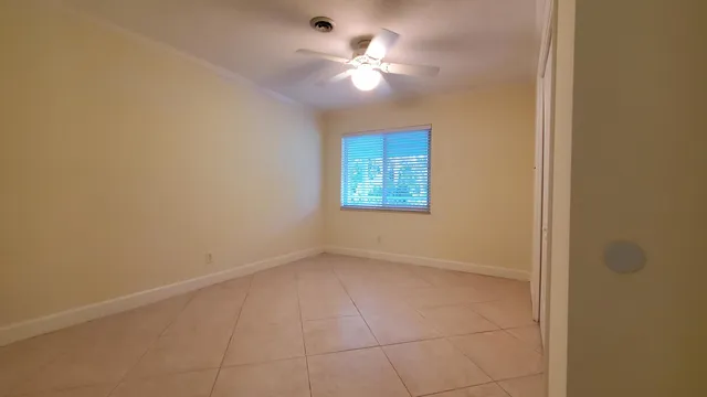 an empty room with a chandelier fan and windows