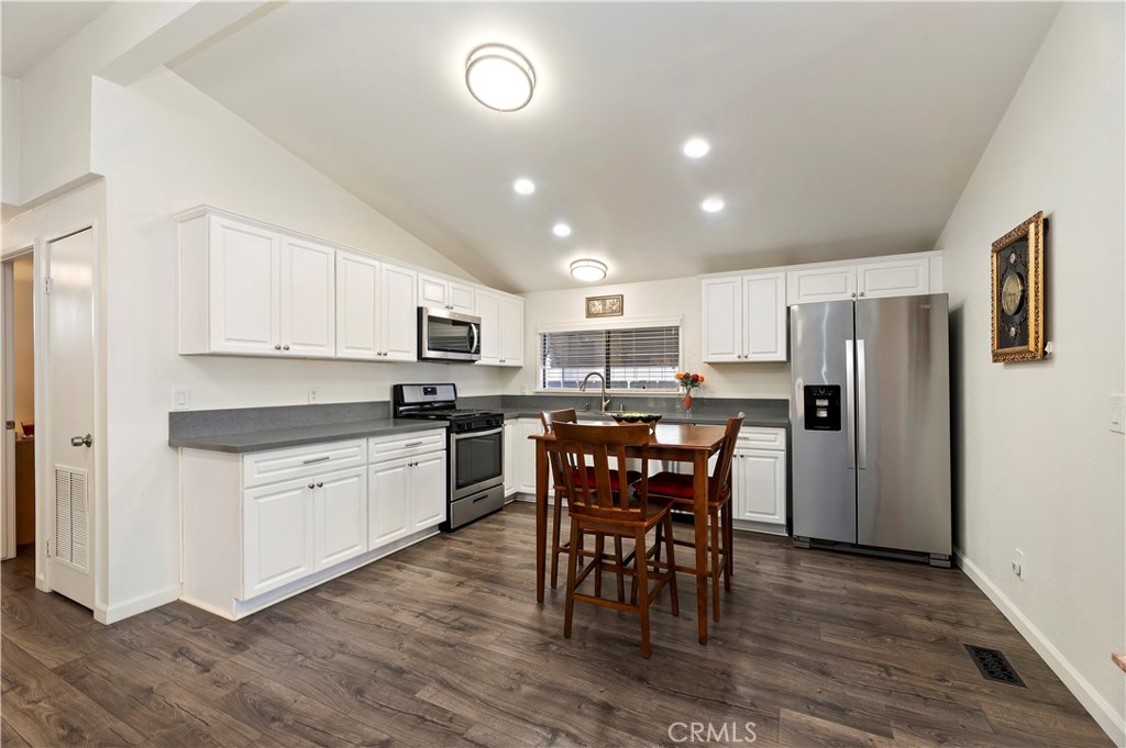 27250 Murrieta Road, Unit 120 Menifee, CA 92586 - Photo 15 of 46 a kitchen with stainless steel appliances granite countertop a refrigerator a stove top oven a sink dishwasher and a dining table with wooden floor