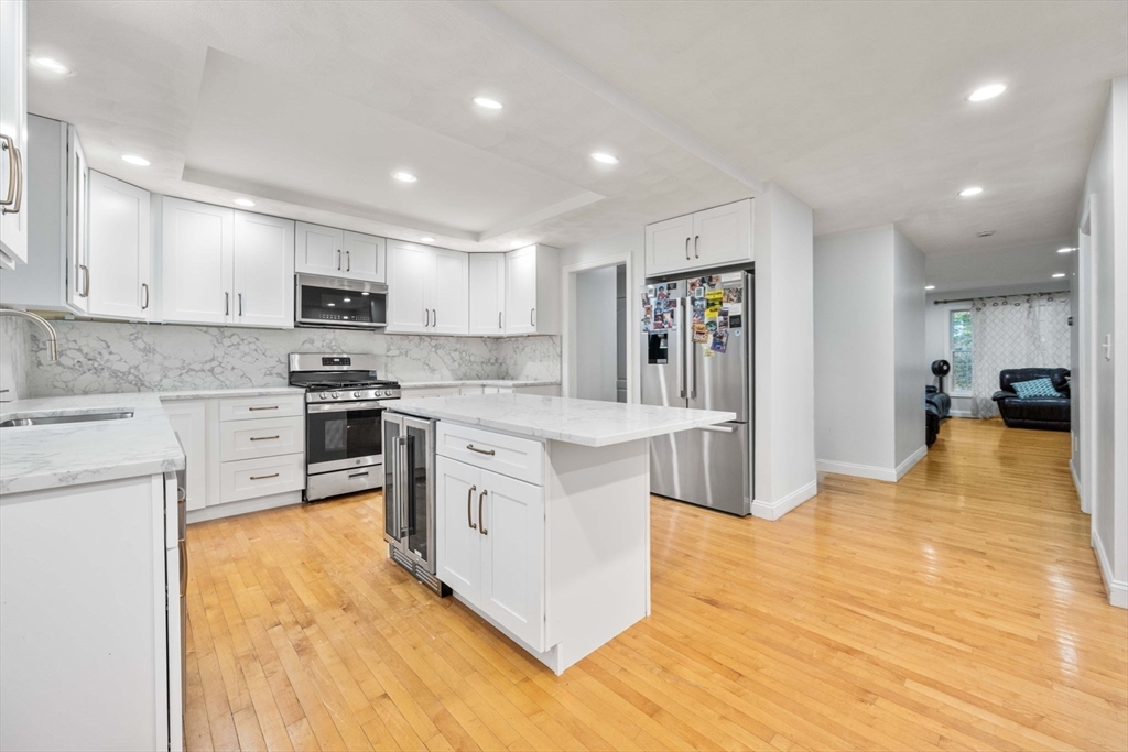 772 Main Street, Unit 2 Wakefield, MA 01880 - Photo 9 of 30 a large kitchen with stainless steel appliances granite countertop a stove a sink dishwasher and a refrigerator with wooden floor
