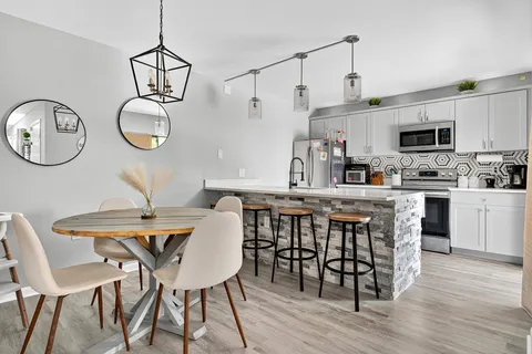 a kitchen with a dining table chairs and white cabinets