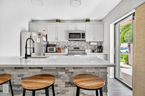 a kitchen with stainless steel appliances granite countertop a stove a sink a microwave a refrigerator and cabinets