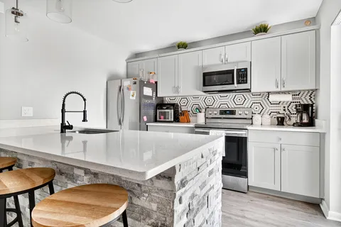 a kitchen with stainless steel appliances granite countertop a sink a stove a microwave a counter space and cabinets