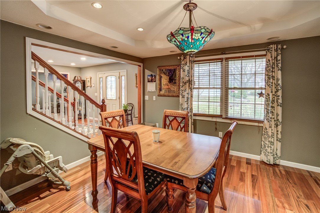 Dining area with a tray ceiling, an inviting chandelier, and hardwood / wood-style flooring
