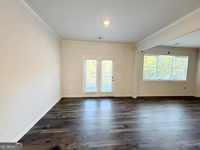 an empty room with wooden floor and windows