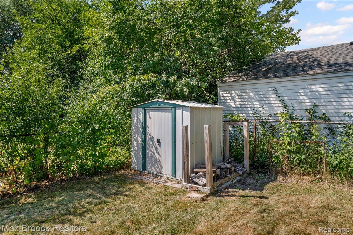 42470 Bishop Road Canton, MI 48188 - Photo 29 of 37 Backyard retreat featuring a modern metal storage shed with sliding doors and concrete foundation, surrounded by mature tree coverage and established landscaping