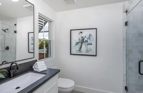 a bathroom with a granite countertop sink a toilet and a mirror