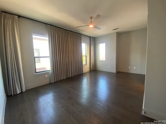 an empty room with hard wood floors and windows