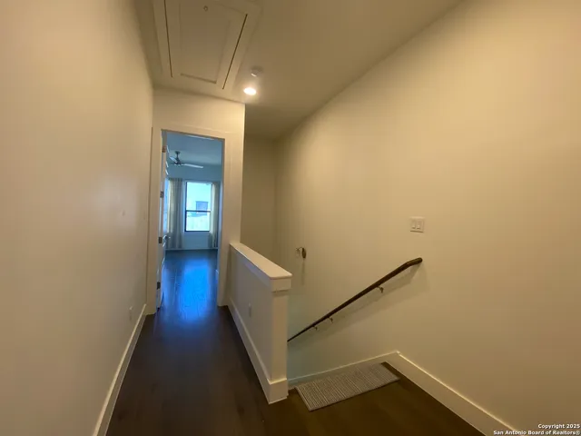 an empty room with wooden floor chandelier and windows