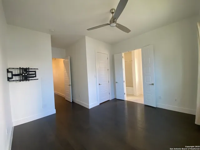 an empty room with wooden floor cabinet and windows