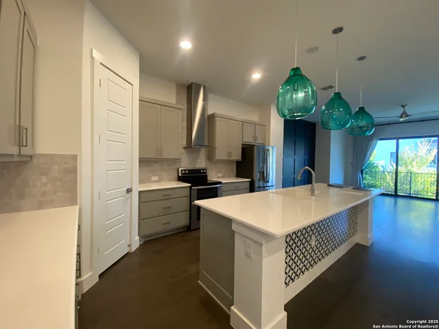 a kitchen that has a lot of white cabinets and stainless steel appliances
