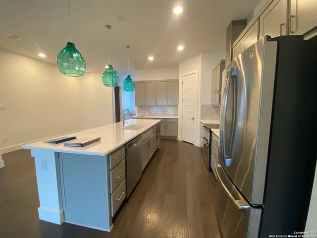 a kitchen with stainless steel appliances a refrigerator a sink a stove and a refrigerator