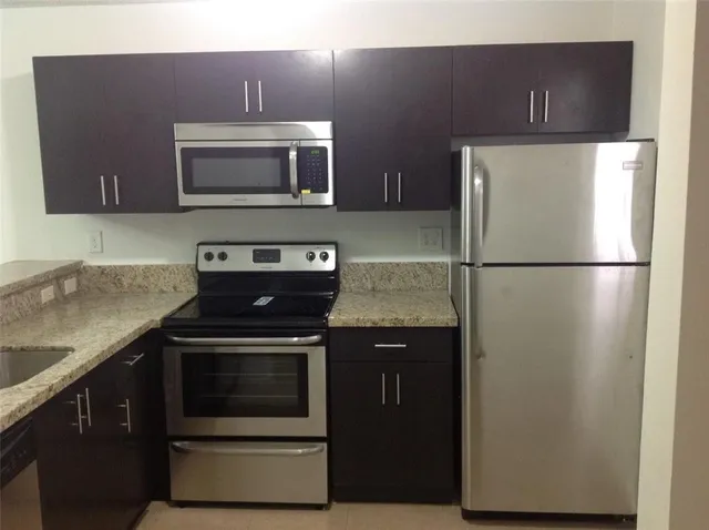 a kitchen with granite countertop a stove microwave and sink