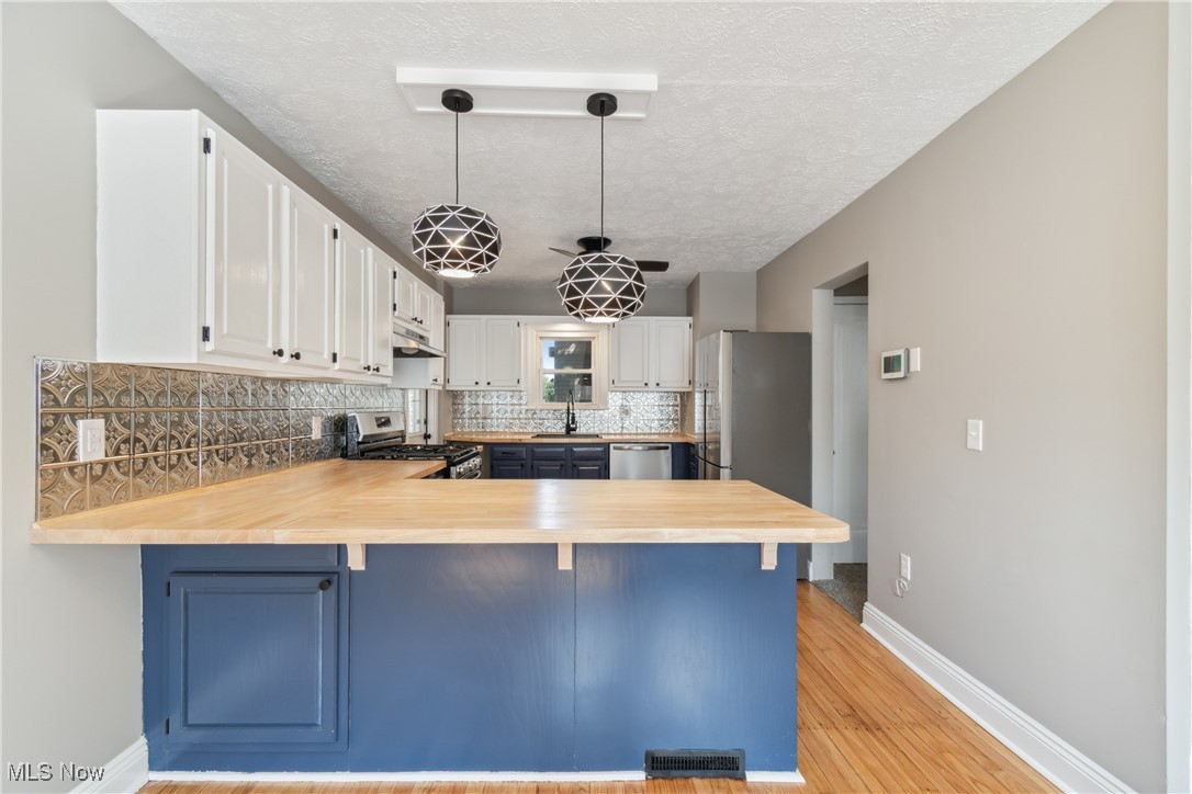 451 West Waterloo Road Akron, OH 44314 - Photo 7 of 27 Kitchen featuring appliances with stainless steel finishes, light wood-type flooring, pendant lighting, and white cabinets