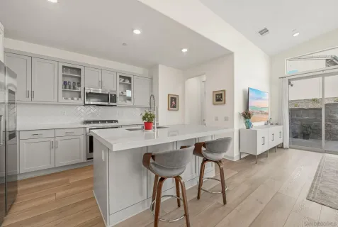 a kitchen with stainless steel appliances a sink a stove a refrigerator cabinets and chairs