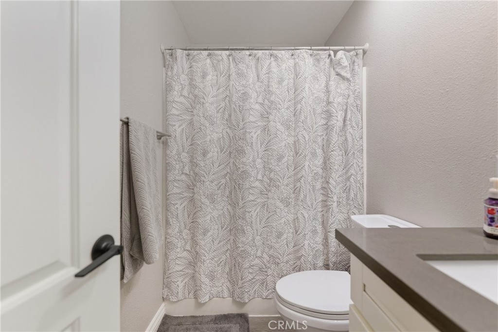 24150 Rothbury Drive Moreno Valley, CA 92553 - Photo 19 of 26 a white toilet sitting next to a shower curtain
