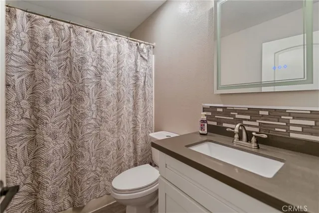 a bathroom with a granite countertop sink and a toilet