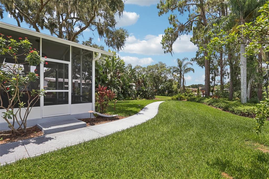 2512 Baywater Road Tavares, FL 32778 - Photo 35 of 75 a view of a white house with a big yard and potted plants and trees
