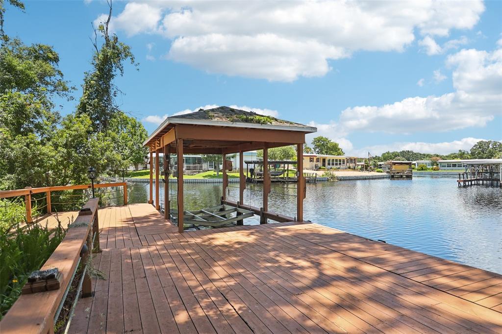 2512 Baywater Road Tavares, FL 32778 - Photo 43 of 75 a patio with a table and chairs under an umbrella with large trees