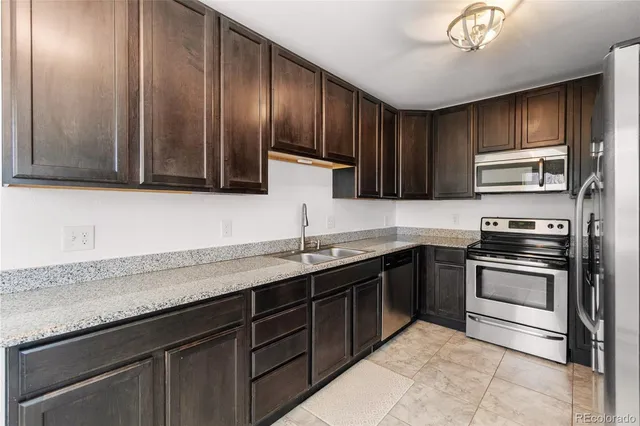 a kitchen with stainless steel appliances granite countertop wooden cabinets a stove top oven a sink and dishwasher