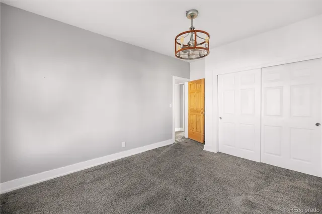 a view of an empty room with a chandelier fan