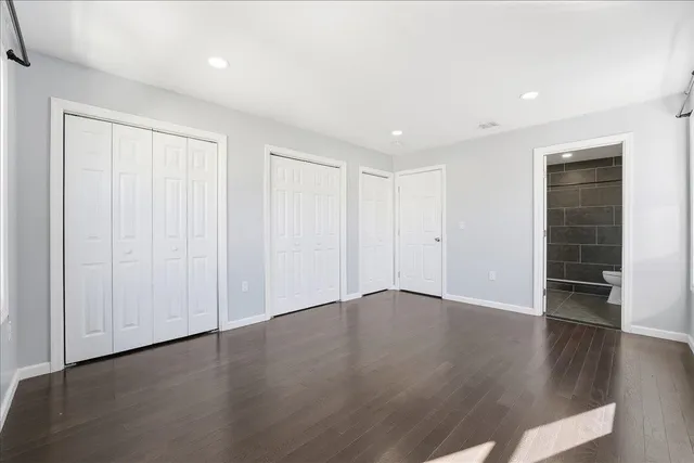 an empty room with wooden floor & closet area
