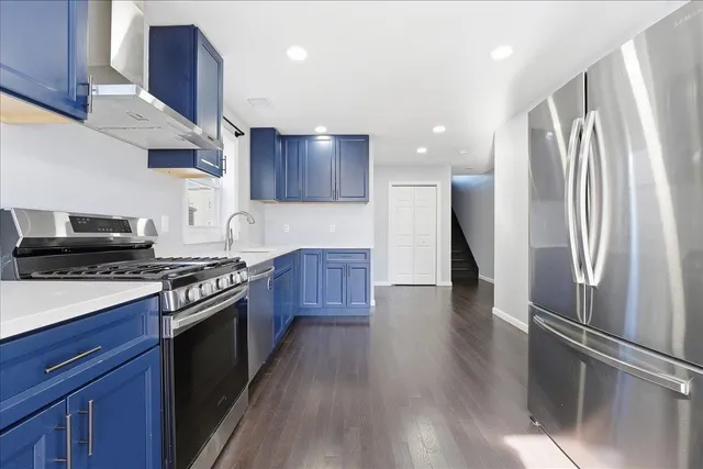 a kitchen with stainless steel appliances granite countertop a stove a refrigerator and a view of wooden floors
