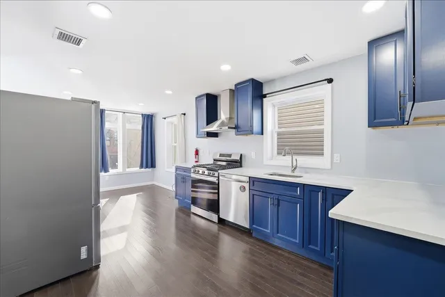 a kitchen with stainless steel appliances granite countertop wooden cabinets a sink dishwasher a stove and a refrigerator with wooden floor