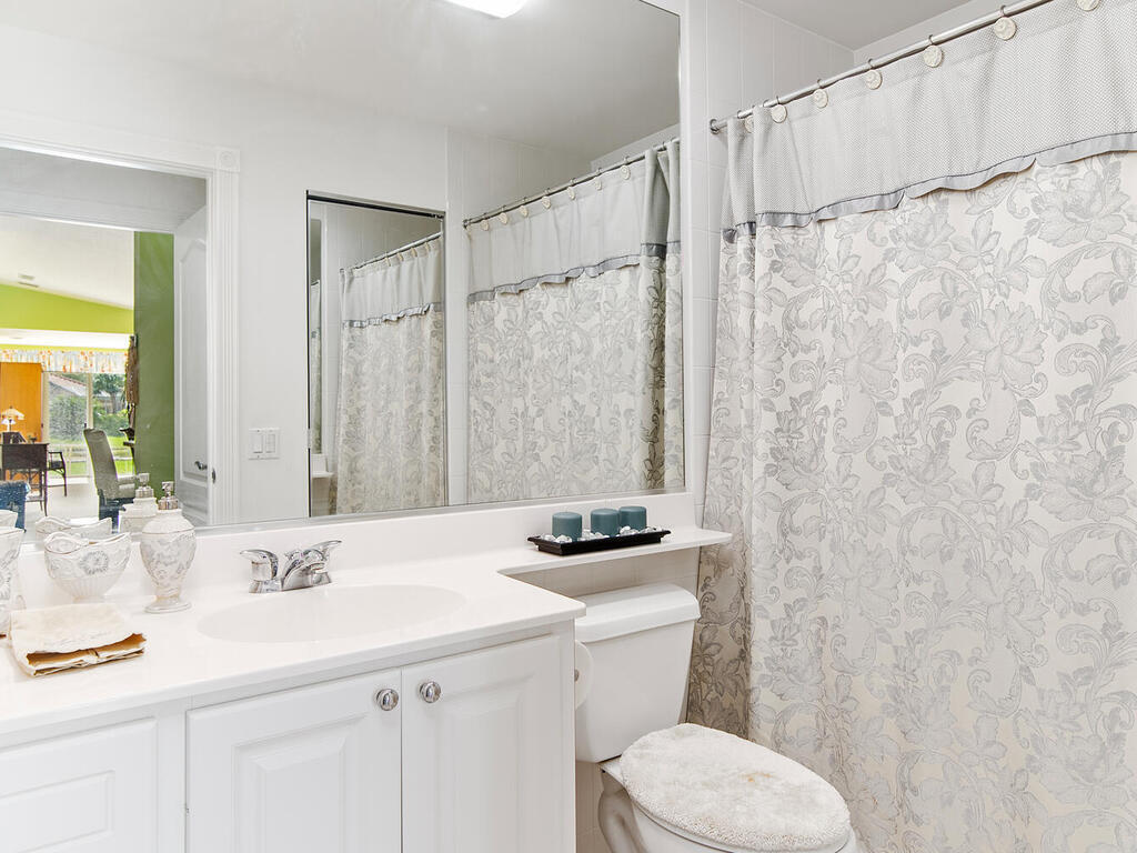 3074 Futuna Lane Naples, FL 34119 - Photo 19 of 28 a bathroom with a sink a toilet a mirror and shower curtain