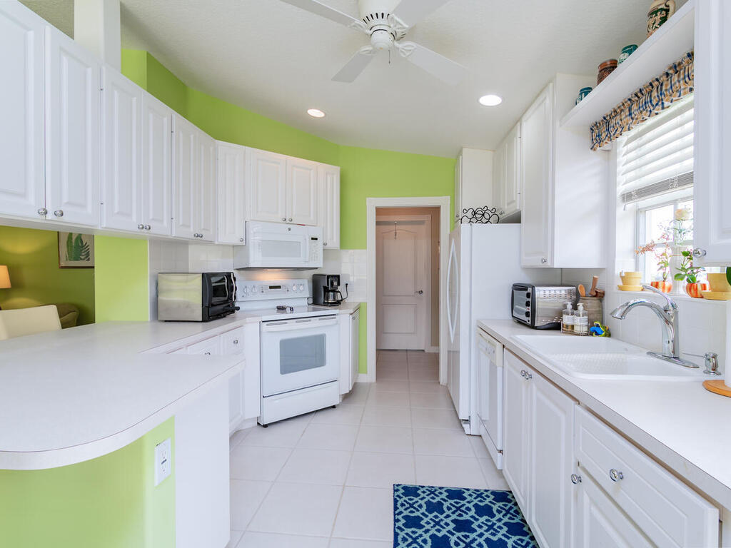 3074 Futuna Lane Naples, FL 34119 - Photo 8 of 28 a kitchen with white cabinets and white appliances