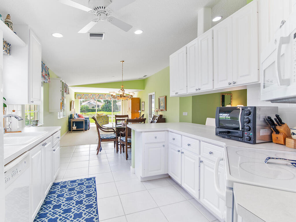3074 Futuna Lane Naples, FL 34119 - Photo 9 of 28 a kitchen with white cabinets and white appliances