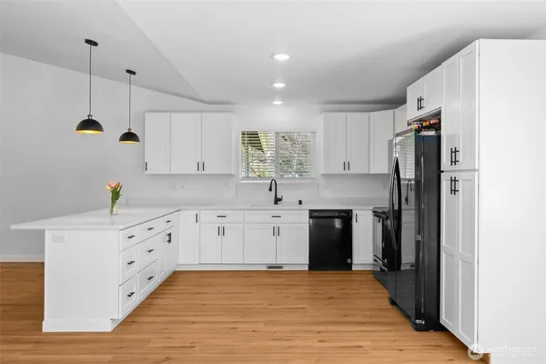 a kitchen with granite countertop a refrigerator oven a sink and white cabinets