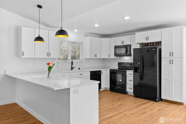 a kitchen with stainless steel appliances kitchen island granite countertop a sink a stove a refrigerator cabinets and wooden floor