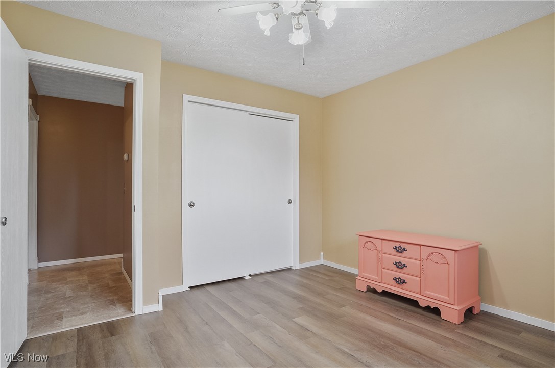 3262 Wright Road Northwest Uniontown, OH 44685 - Photo 27 of 37 Unfurnished bedroom with wood finished floors, a textured ceiling, a closet, and ceiling fan