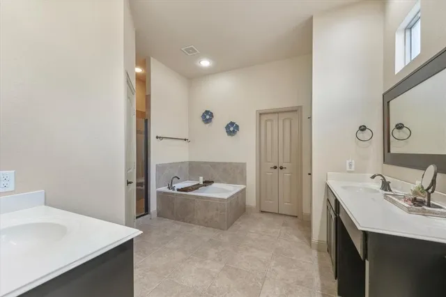 a bathroom with a sink double vanity granite tub shower and mirror